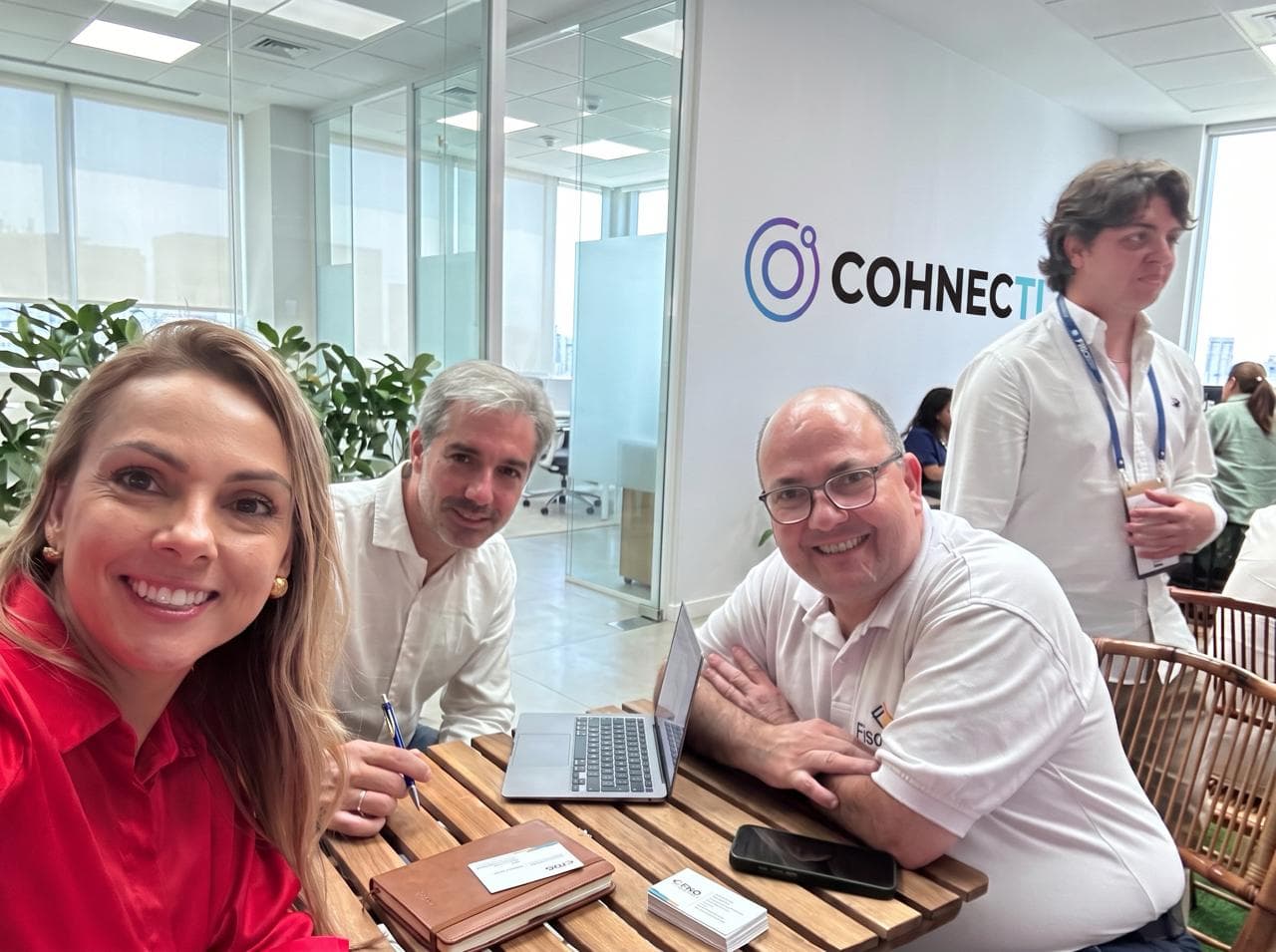 Personas reunidas en una oficina de COHNECTI, con el logo de la empresa al fondo